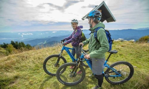 The two cyclists taking a rest at a peak of a mountain with a beautiful background